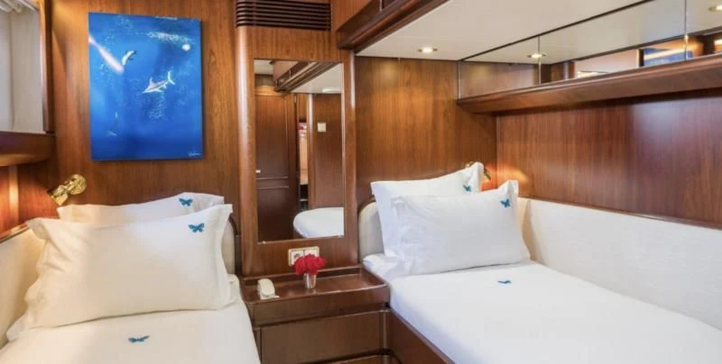 a room with beds and a mirror aboard BLUE PAPILLON Yacht for Sale