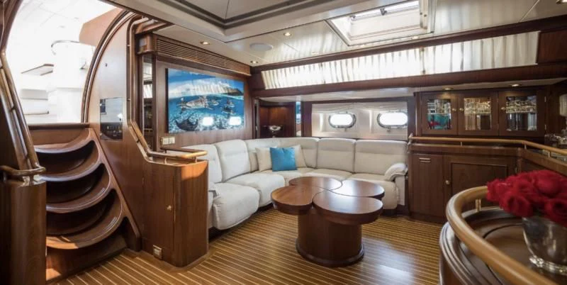a living room with a large wood cabinet and a table aboard BLUE PAPILLON Yacht for Sale