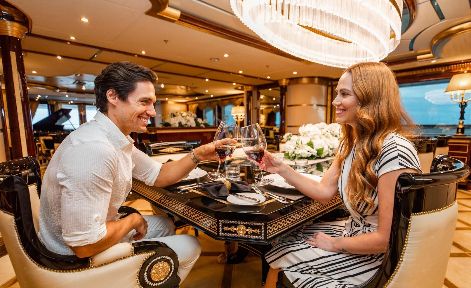 a man and woman sitting at a table with wine glasses aboard SORRENTO Yacht for Sale