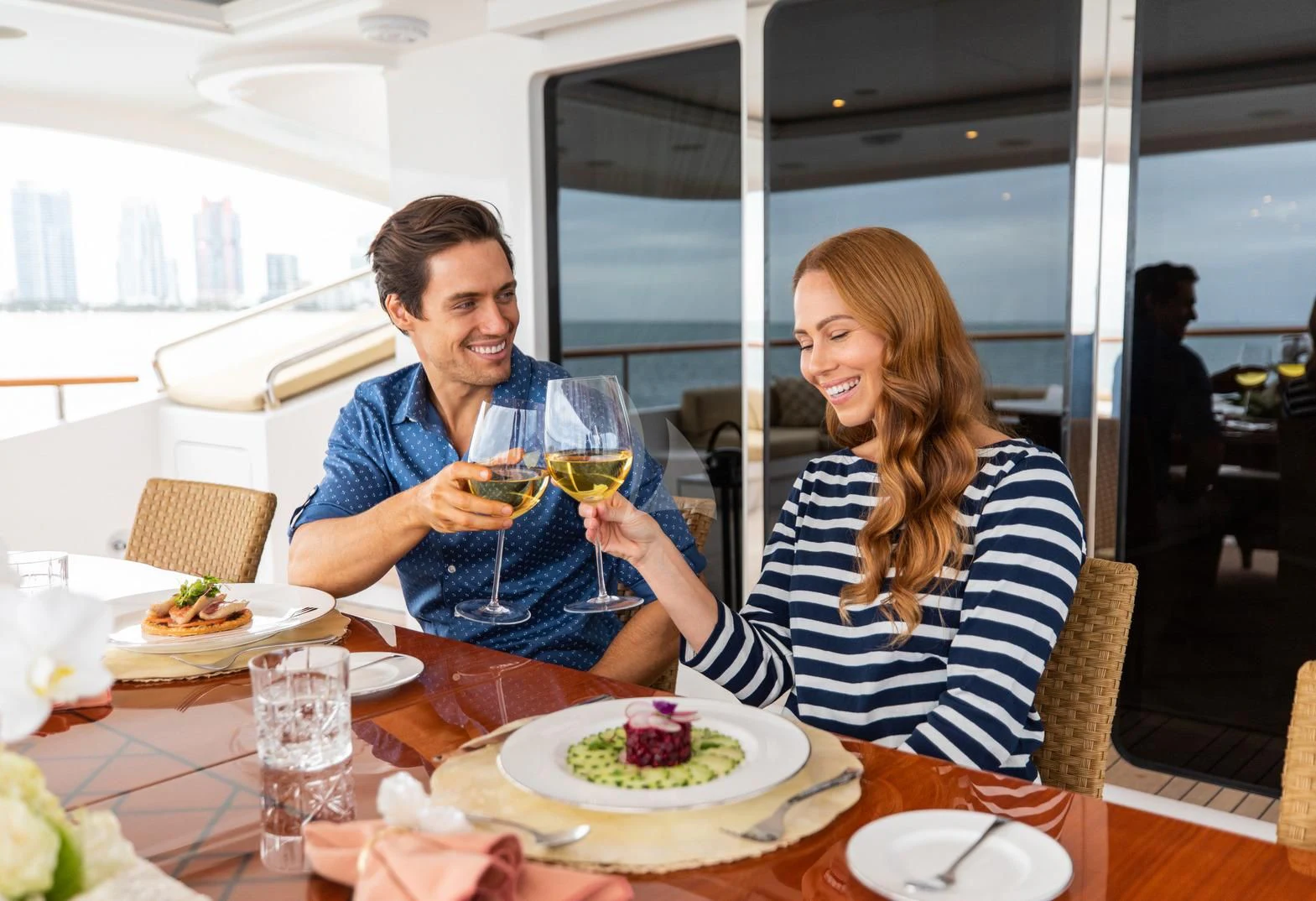 a man and woman sitting at a table with food and drinks aboard SORRENTO Yacht for Sale
