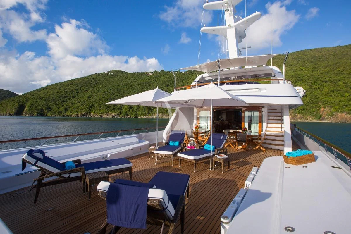 a deck with tables and chairs on it next to a body of water aboard TELEOST Yacht for Sale