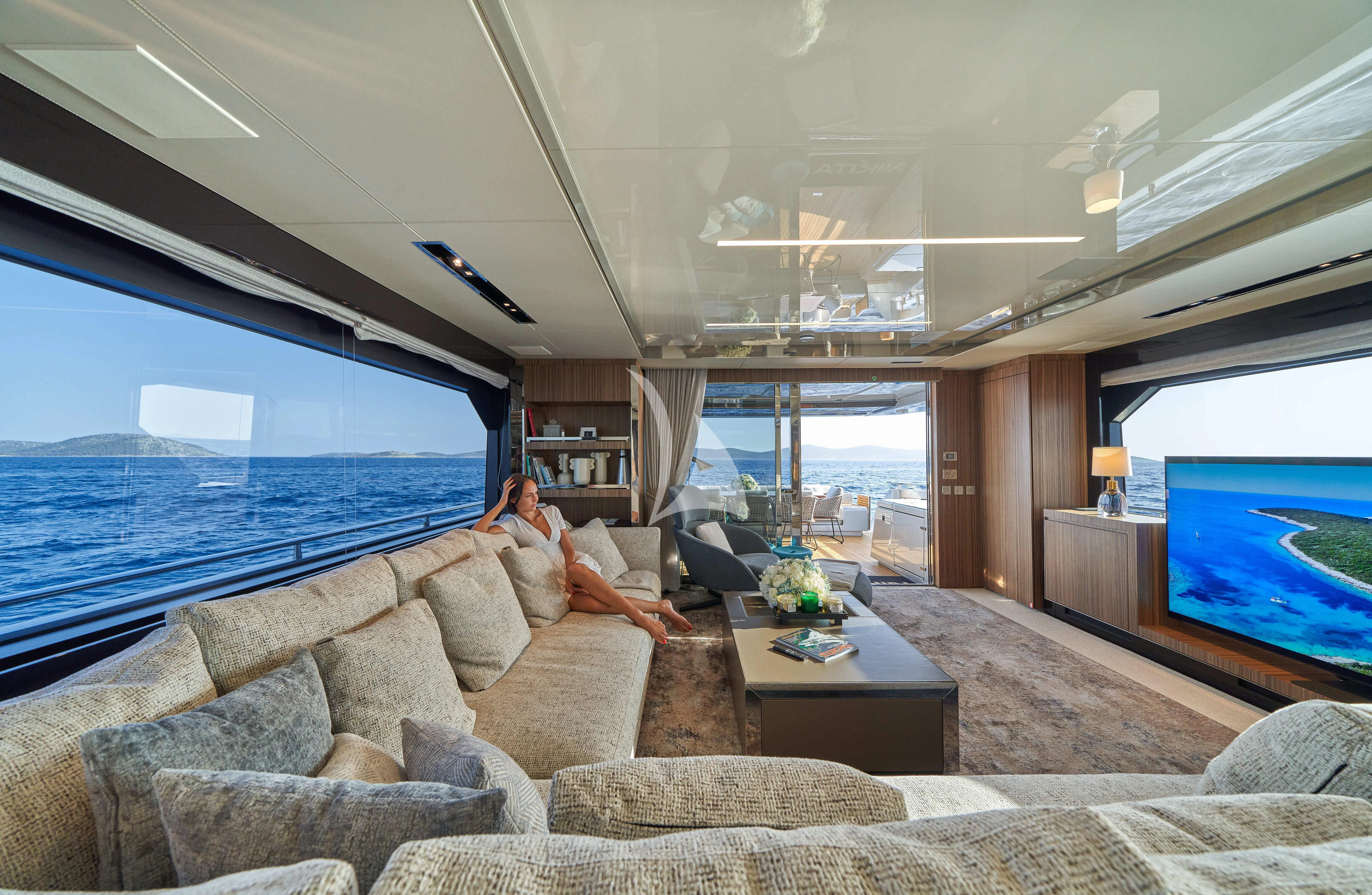 a couple sitting on a couch in front of a large blue ocean aboard NIKITA Yacht for Sale