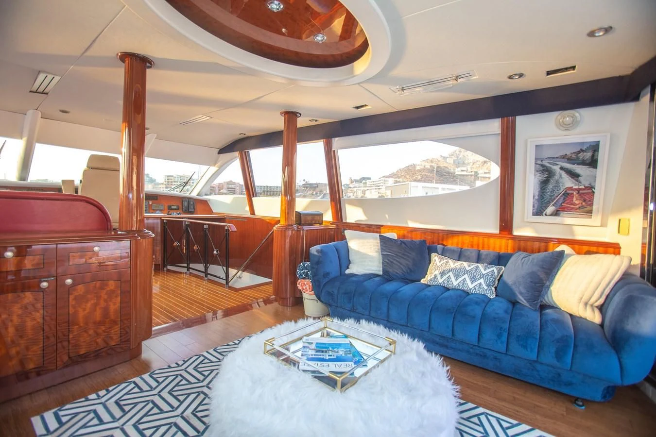 a large living room with a large blue couch and a large window aboard LAZZARA 80' Yacht for Sale