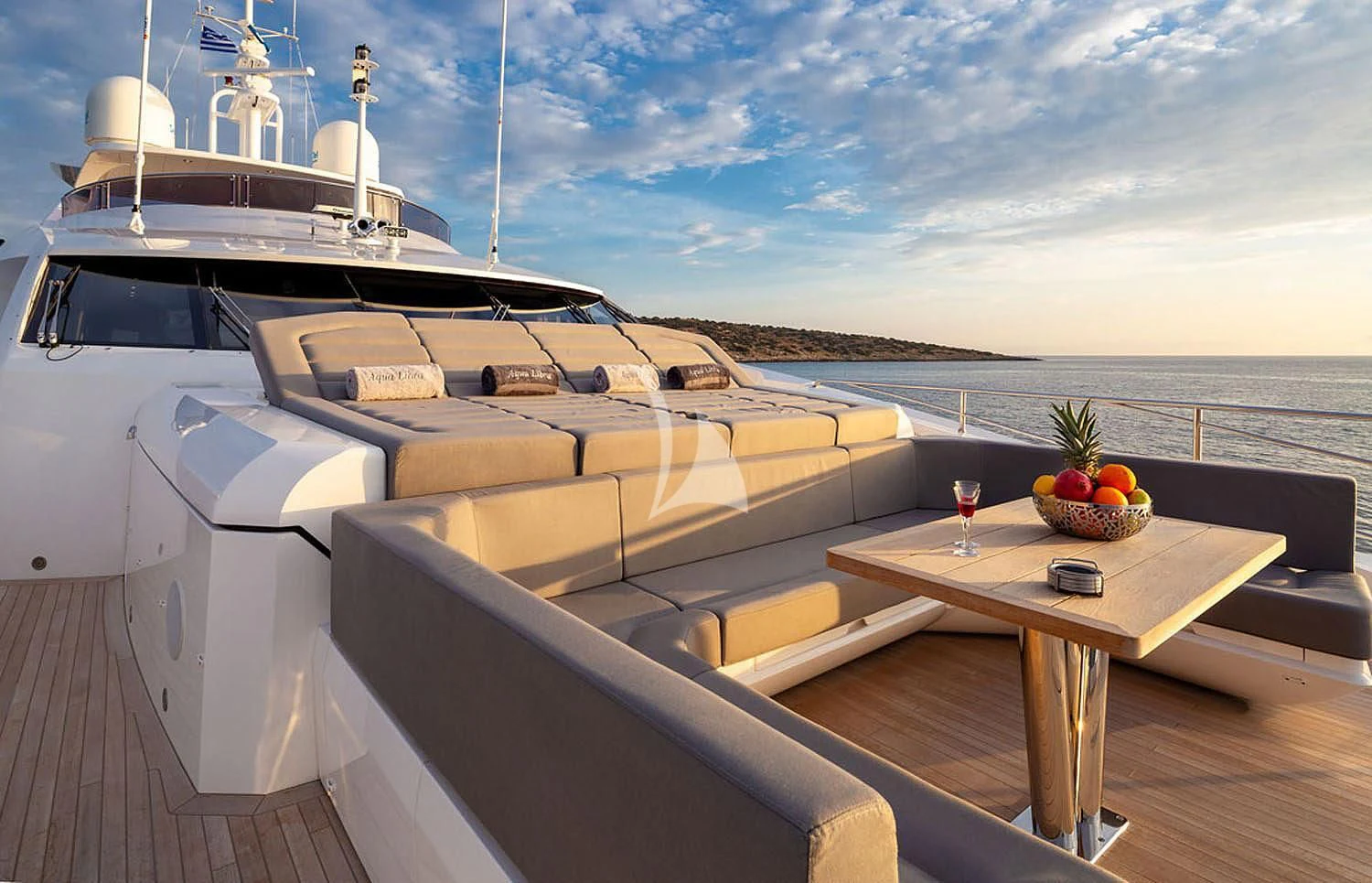 a deck with a table and a boat on it aboard AQUA LIBRA Yacht for Charter