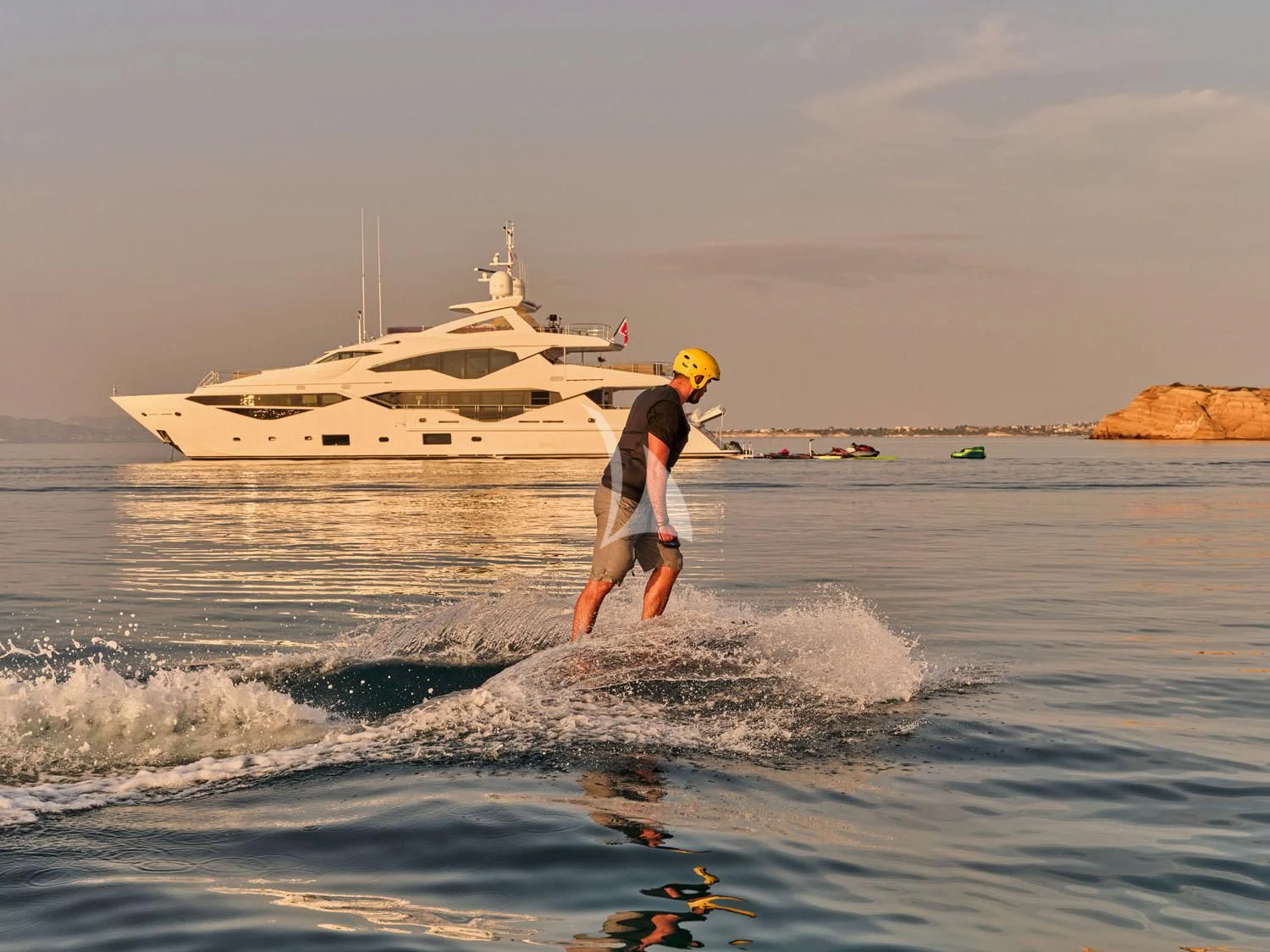 a man in a wet suit in the water with a boat in the background aboard AQUA LIBRA Yacht for Charter