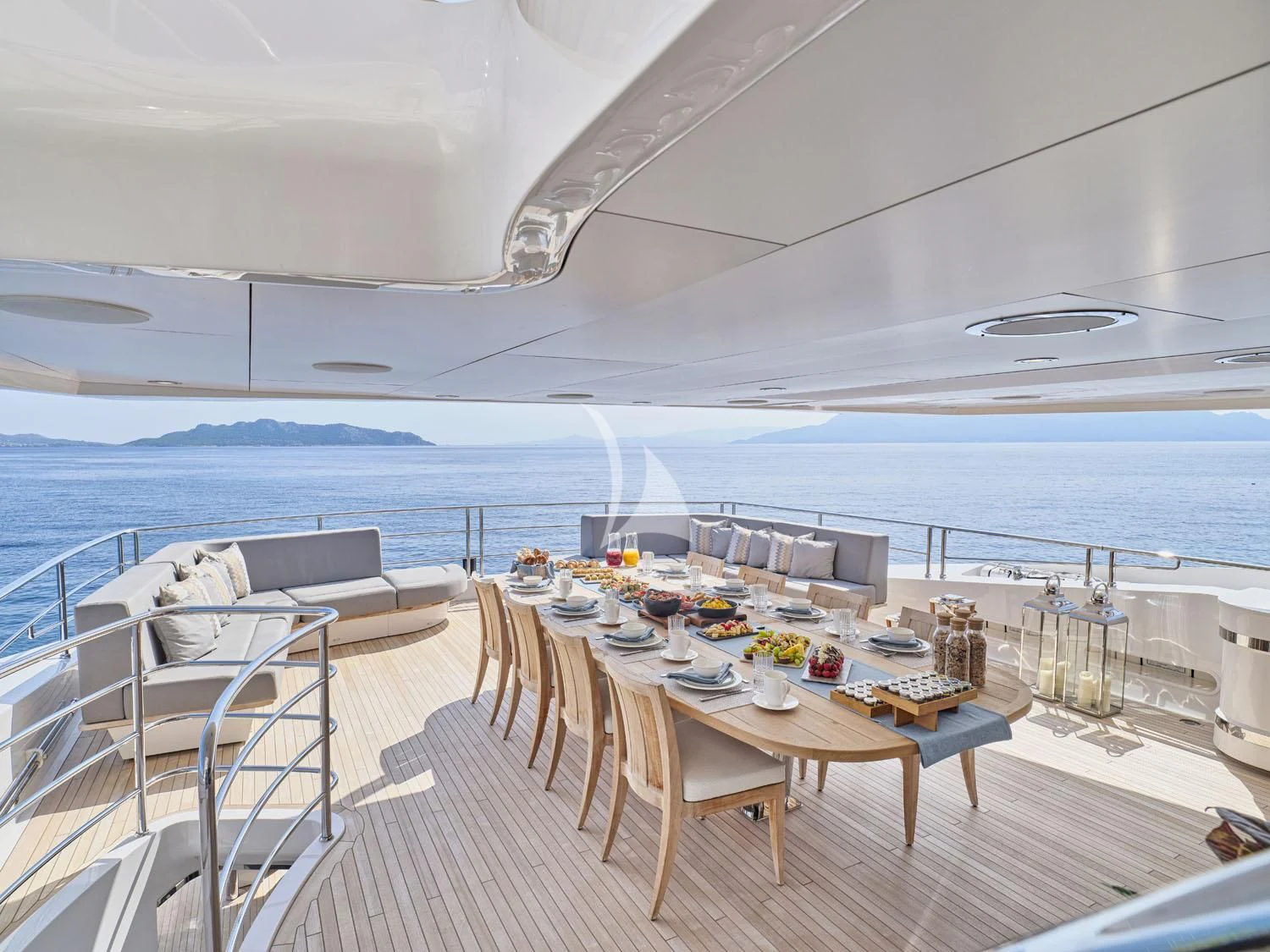 a deck with a large body of water and a large boat in the background aboard AQUA LIBRA Yacht for Charter