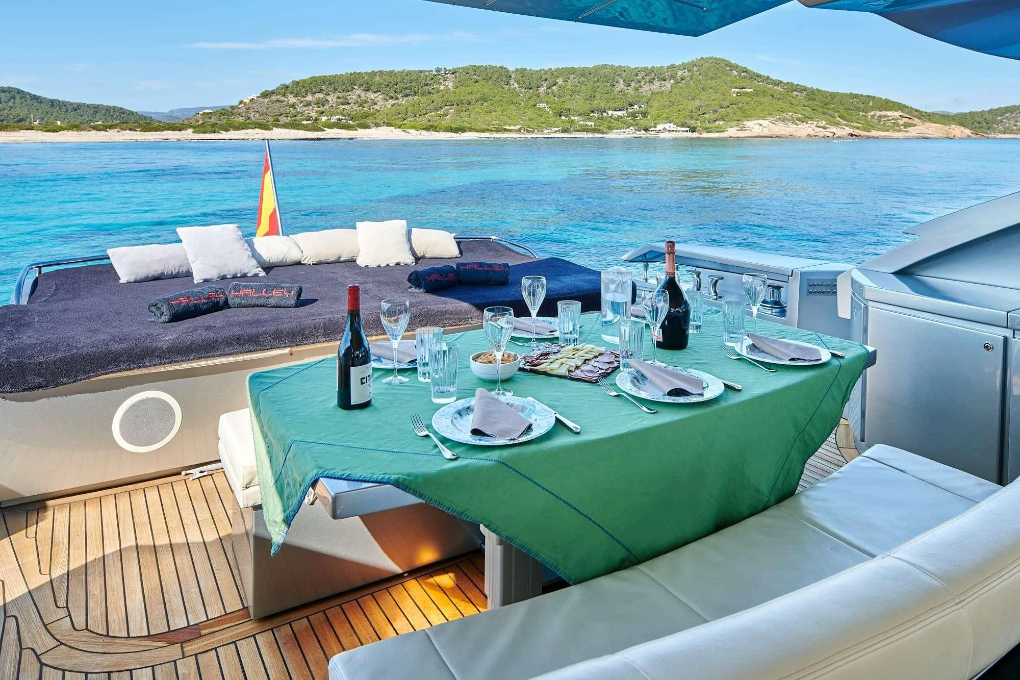a table with wine bottles and glasses on it by a body of water aboard WAHOO Yacht for Sale