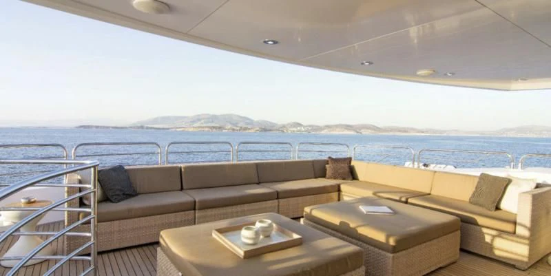 a couch and a table in a room with a view of the ocean aboard PATHOS Yacht for Sale