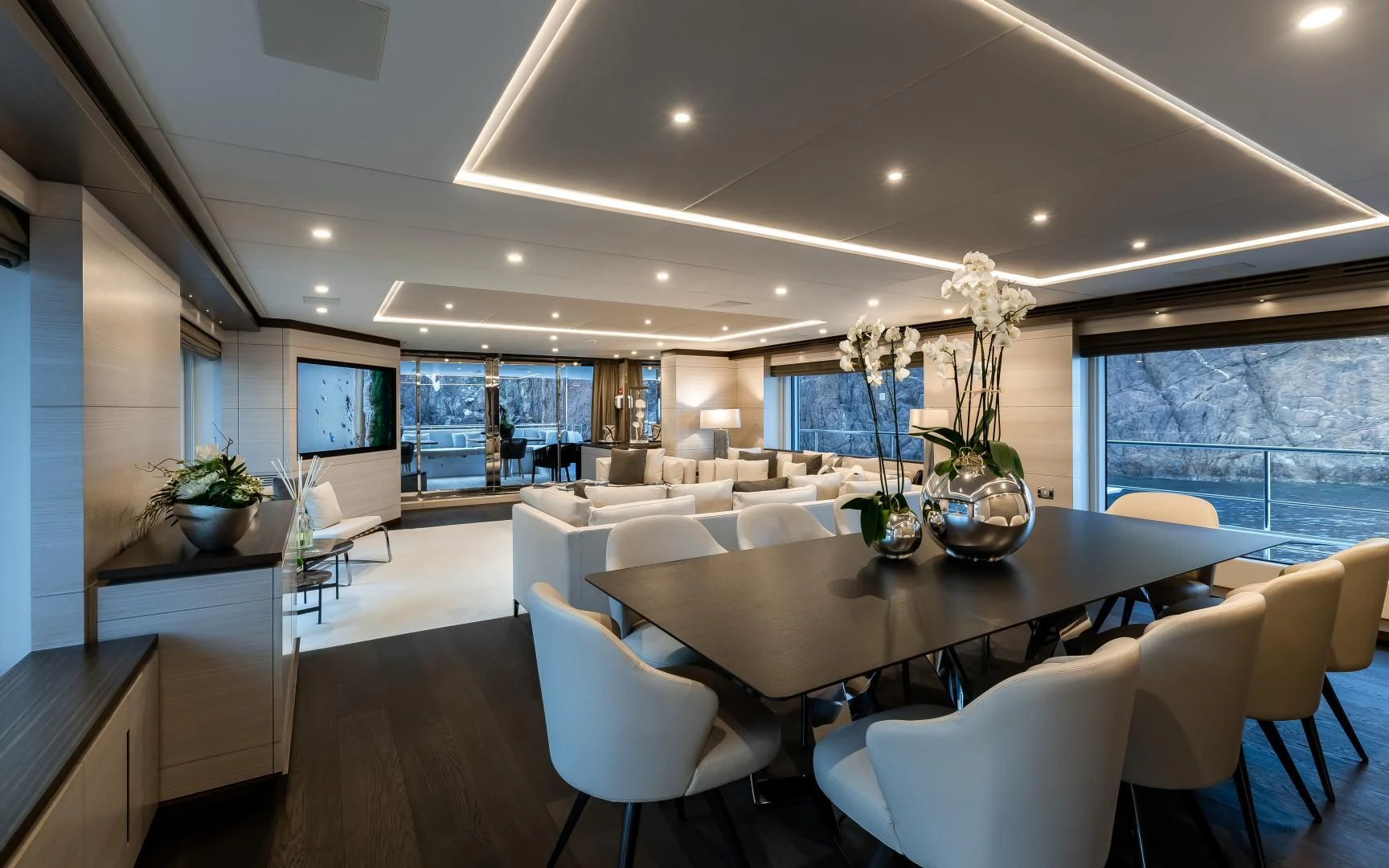a large room with white chairs and a large table with plants in it aboard CALYPSO Yacht for Charter