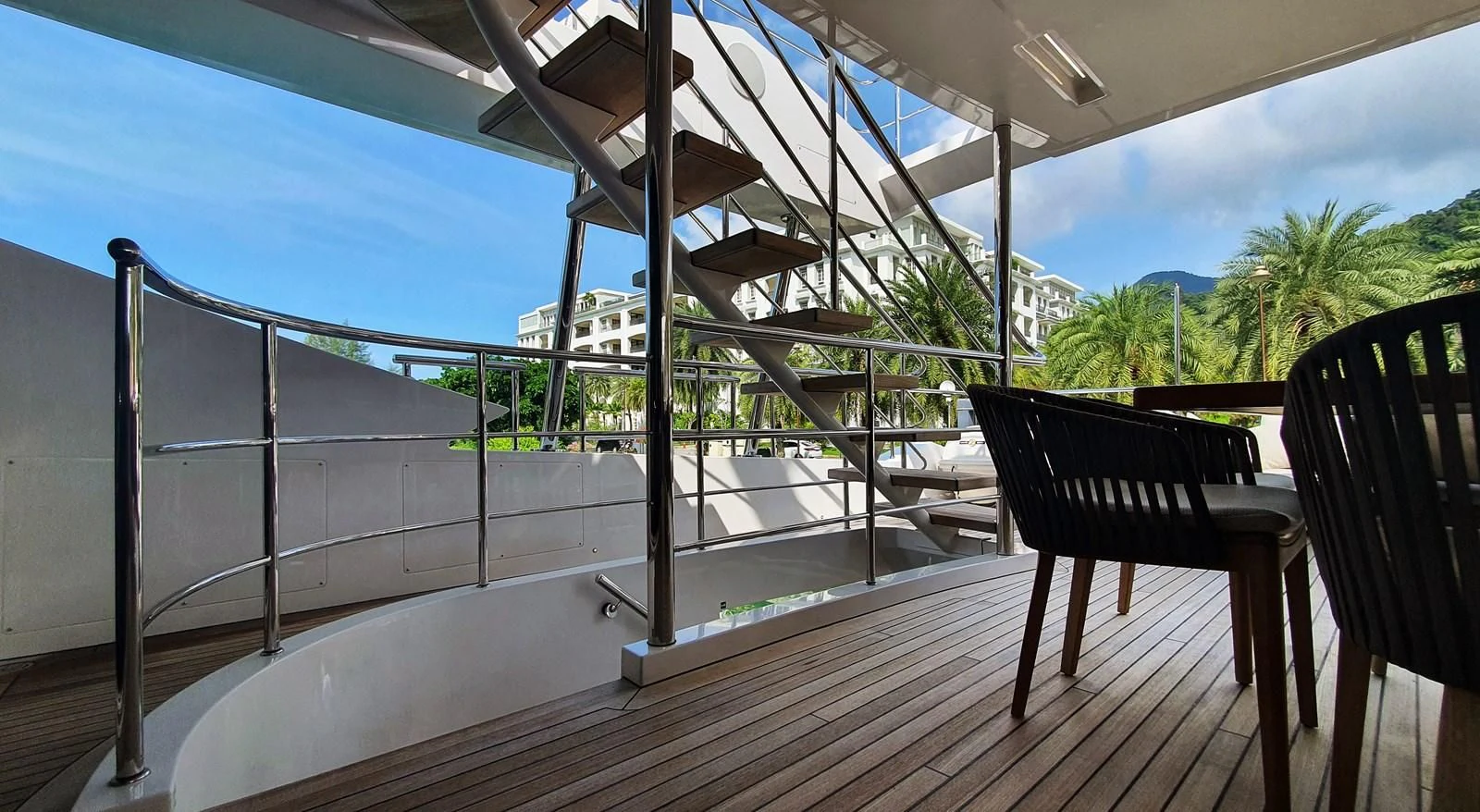 a deck with a chair and a railing and a building in the background aboard CALYPSO Yacht for Charter