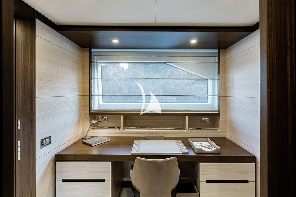a desk with a computer and a window aboard CALYPSO Yacht for Charter