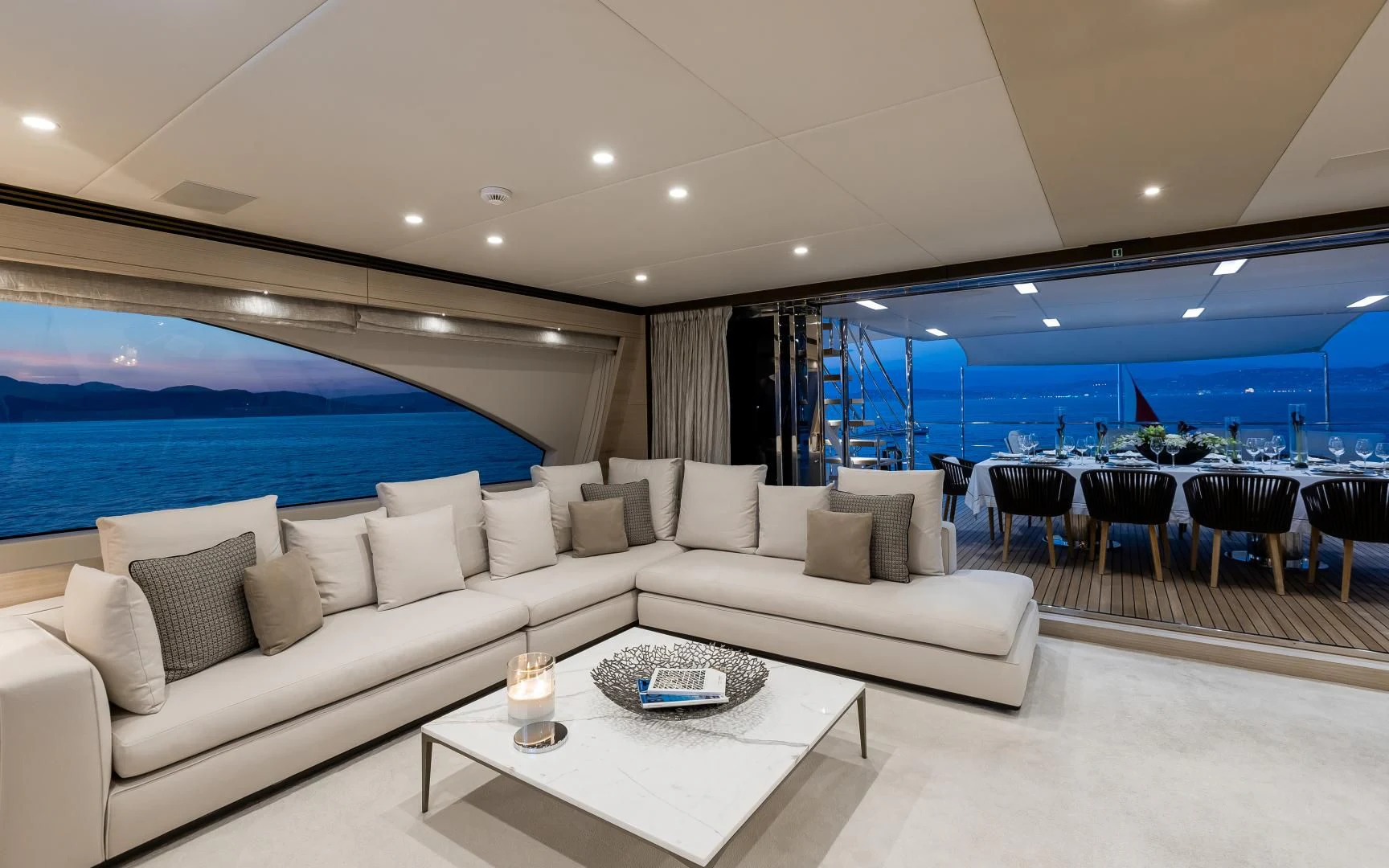 a living room with a large white sofa and a large blue ocean aboard CALYPSO Yacht for Charter