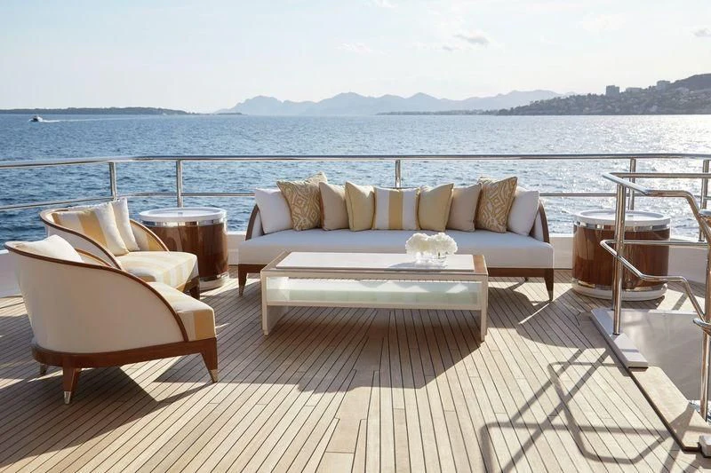 a couch and chairs on a deck overlooking a body of water aboard JOY Yacht for Sale