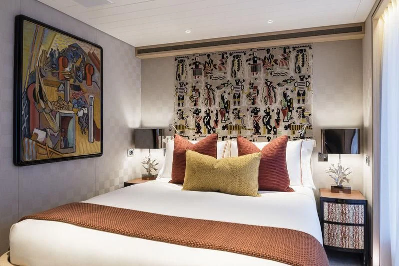 a bed with a painting on the wall aboard JOY Yacht for Sale