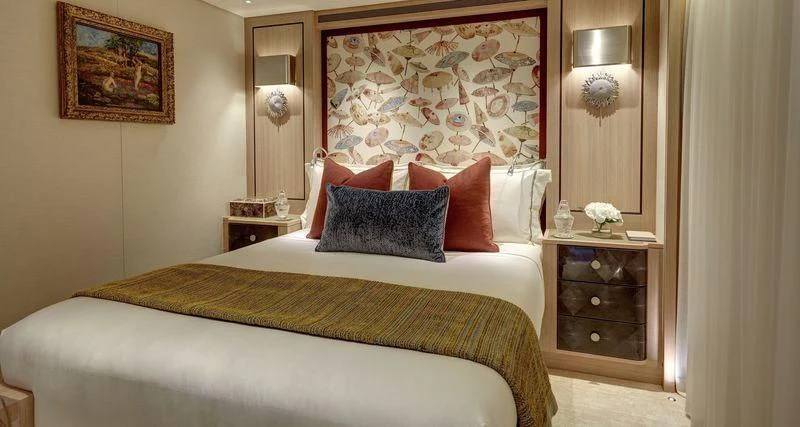a bed with a pillow and a dresser in a room aboard JOY Yacht for Sale