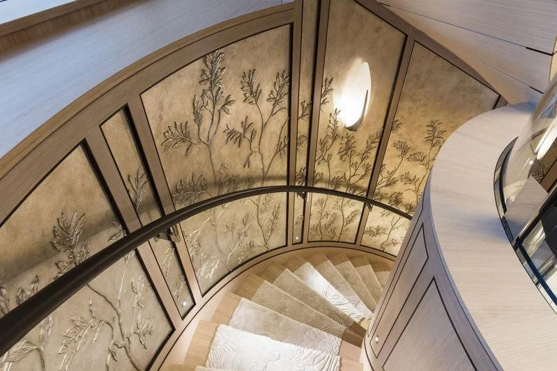 a staircase with a painting on the wall aboard JOY Yacht for Sale