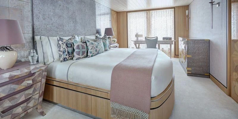 a bed with a white sheet and pillows aboard JOY Yacht for Sale