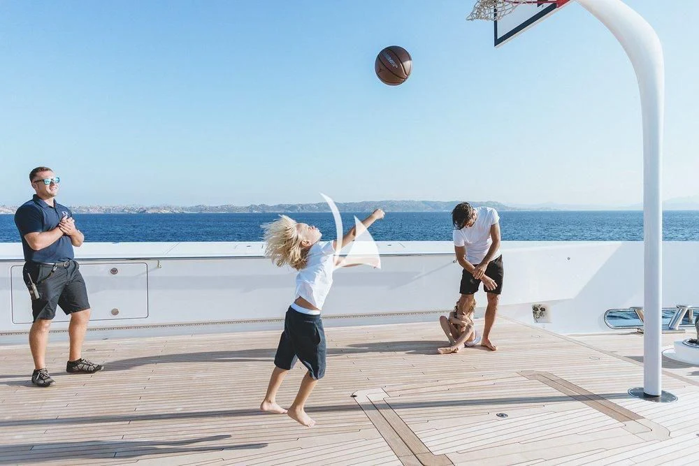 a person playing basketball on a dock aboard JOY Yacht for Sale