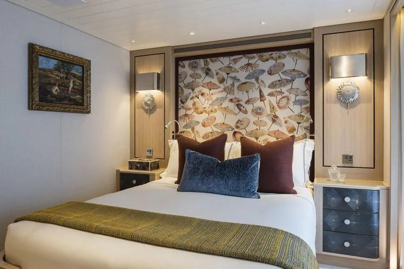 a bed with a painting on the wall aboard JOY Yacht for Sale