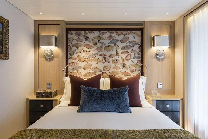 a bed with a painting on the wall aboard JOY Yacht for Sale