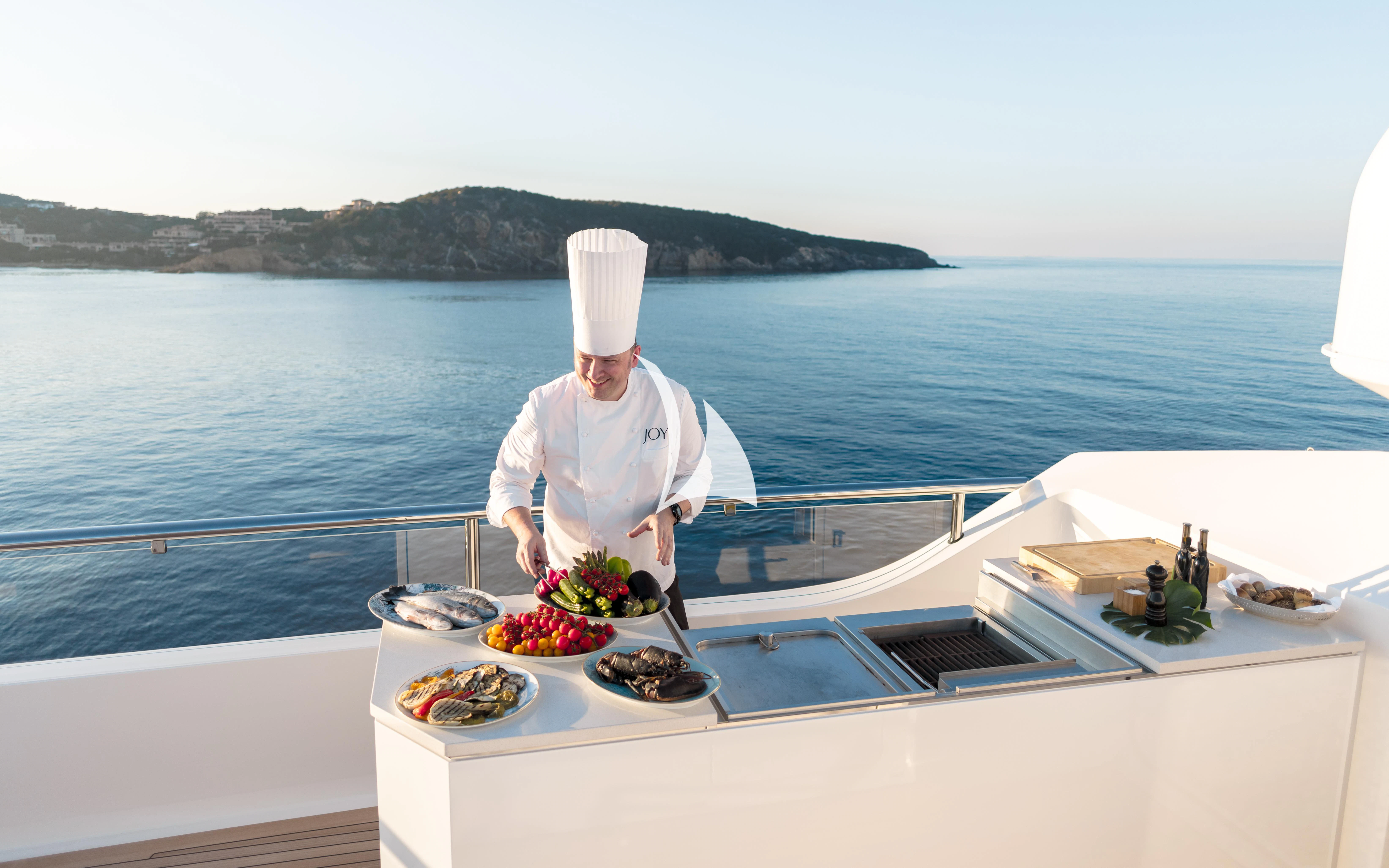 a person in a white robe on a boat with a bowl of fruit aboard JOY Yacht for Sale