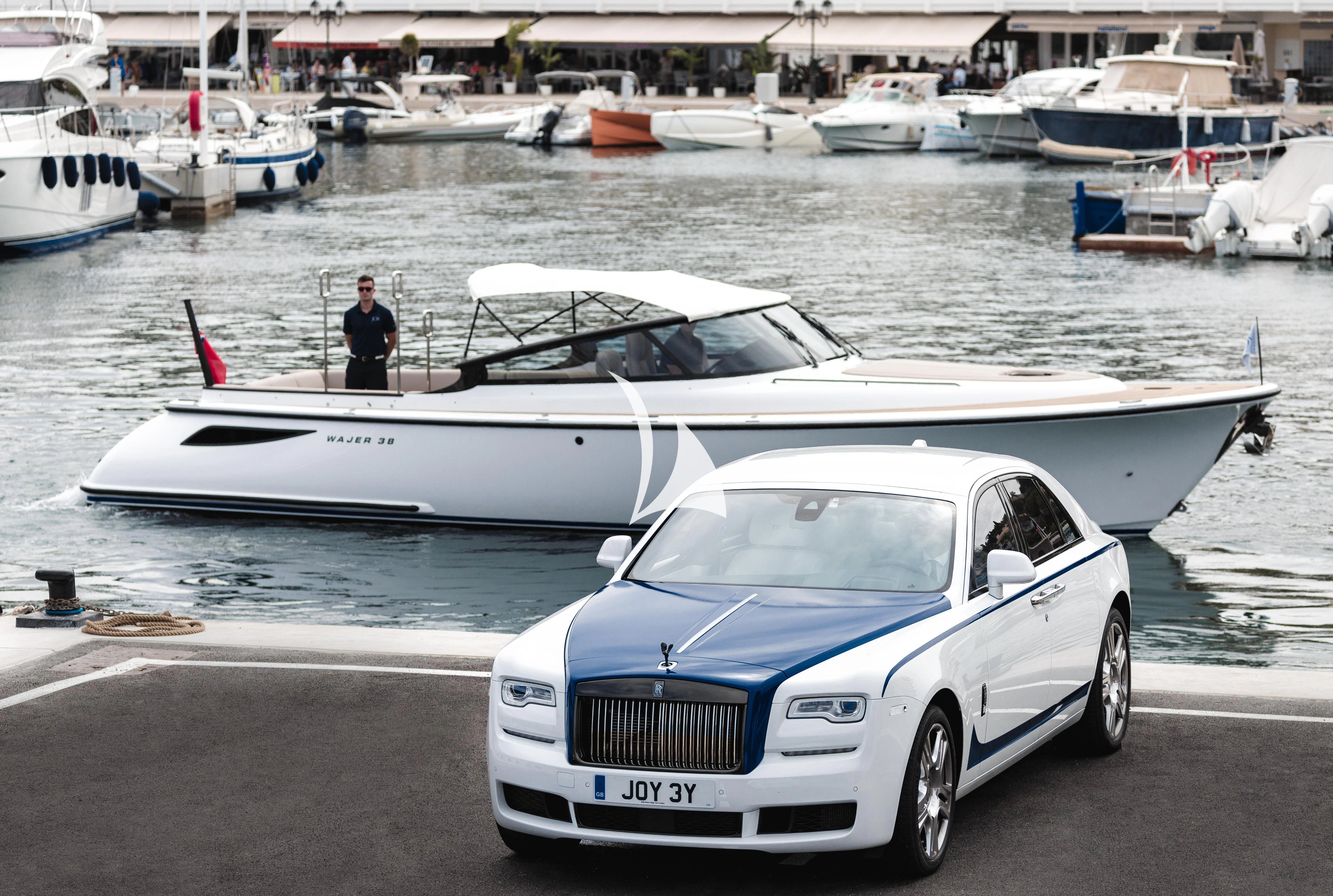 a white car parked next to a white boat in a harbor aboard JOY Yacht for Sale