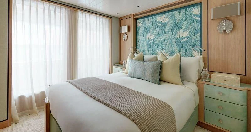 a bedroom with a bed and a dresser aboard JOY Yacht for Sale