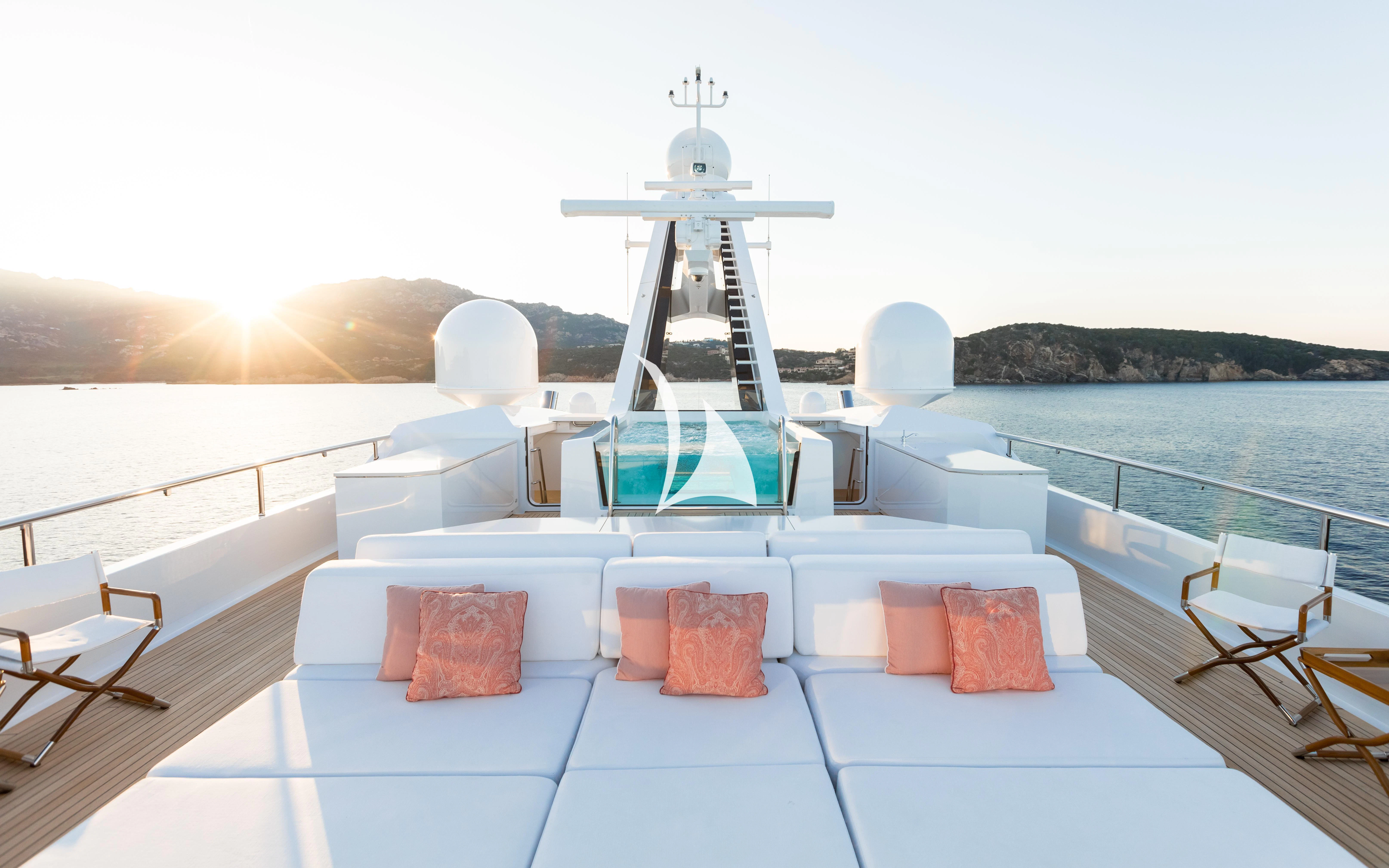 a white and blue lounge chair on a deck overlooking a body of water aboard JOY Yacht for Sale