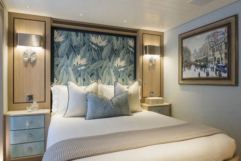 a bed with a painting on the wall aboard JOY Yacht for Sale