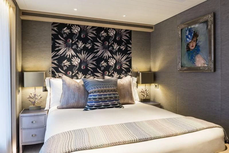 a bed with a painting on the wall aboard JOY Yacht for Sale
