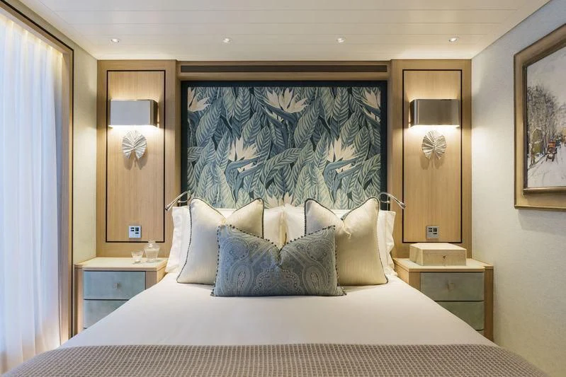 a bed with a painting on the wall aboard JOY Yacht for Sale