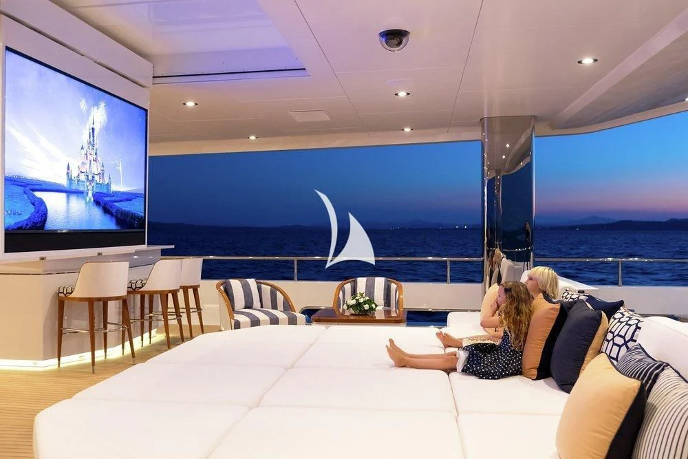a couple sitting on a couch watching tv in a living room aboard JOY Yacht for Sale