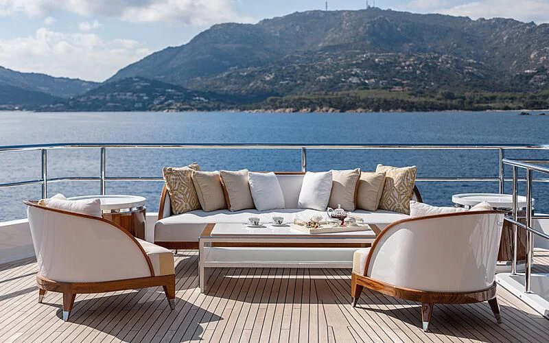 a couch and chairs on a deck overlooking a large body of water aboard JOY Yacht for Sale