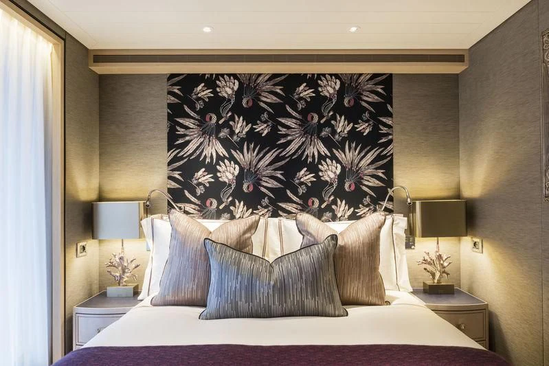 a bed with a painting on the wall aboard JOY Yacht for Sale