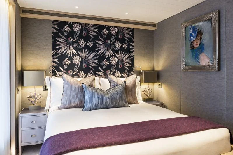 a bed with a painting on the wall aboard JOY Yacht for Sale