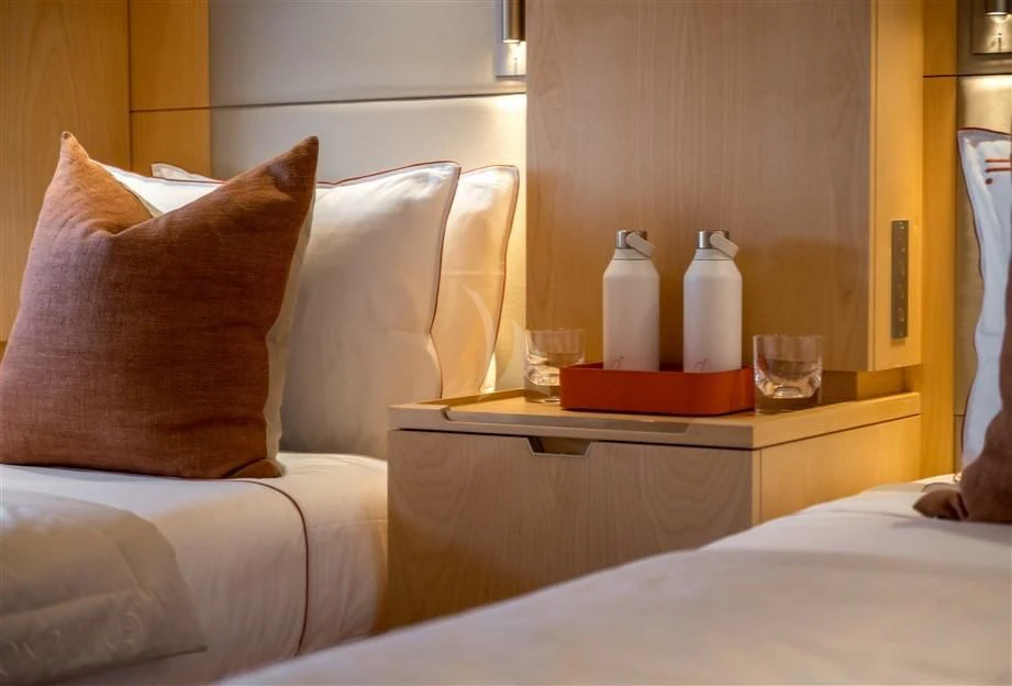 a bed with pillows and a glass of water on it aboard GUILLEMOT Yacht for Sale