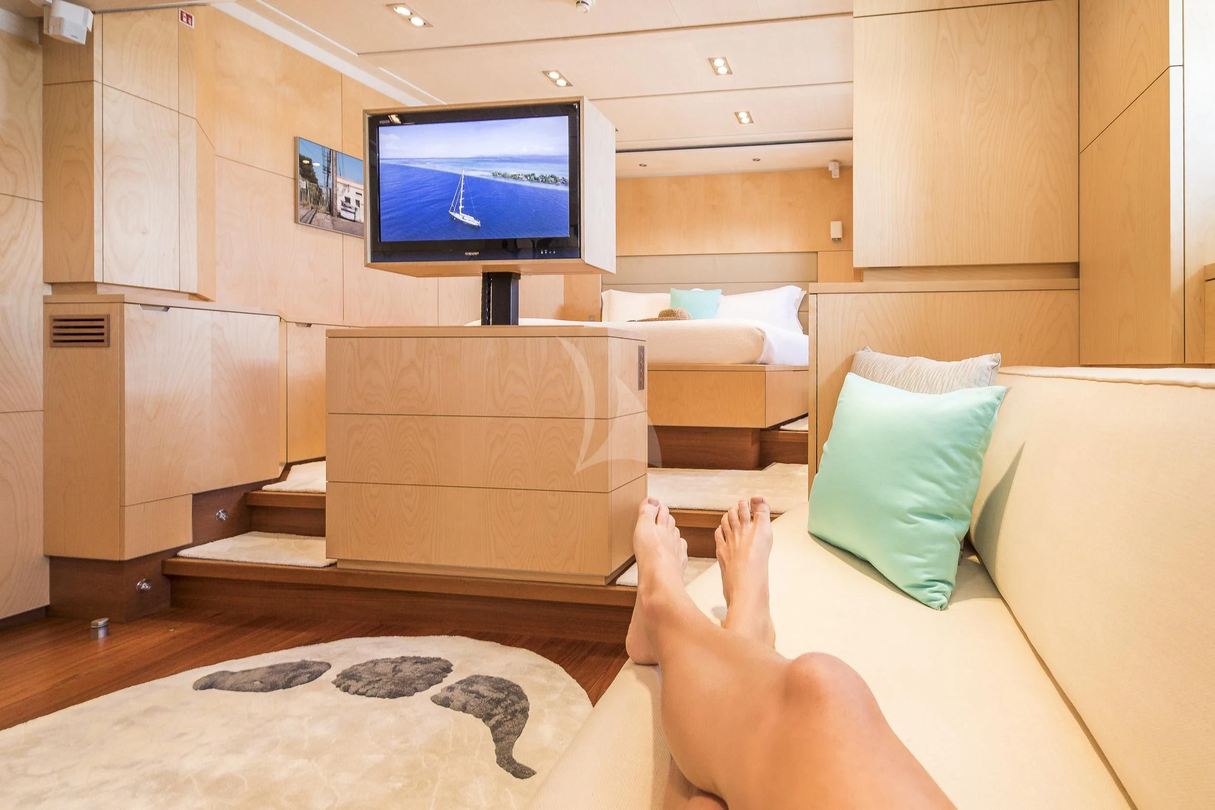 a person's feet on a bed in a room with a tv aboard GUILLEMOT Yacht for Sale