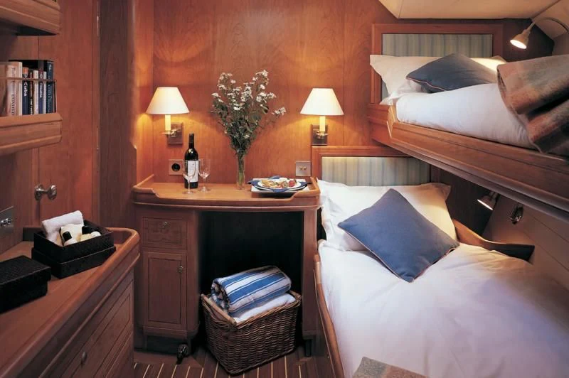 a room with a bed and a table with a lamp on it aboard WAVELENGTH Yacht for Sale