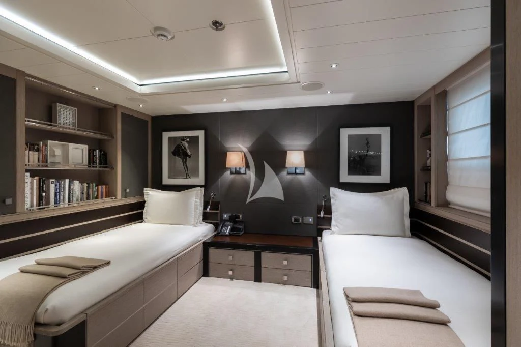 a room with a couple of beds and a shelf with books on it aboard GRACE (YET) Yacht for Sale