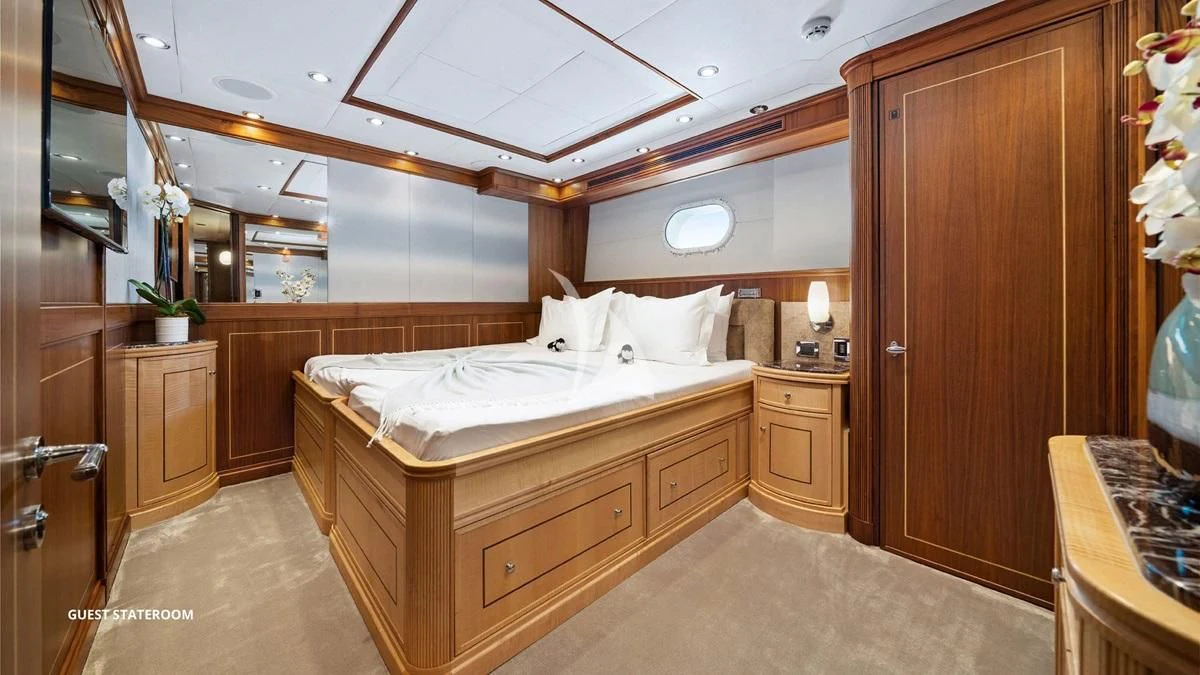a bedroom with a bed and a wood cabinet aboard BLACK SHEEP Yacht for Sale
