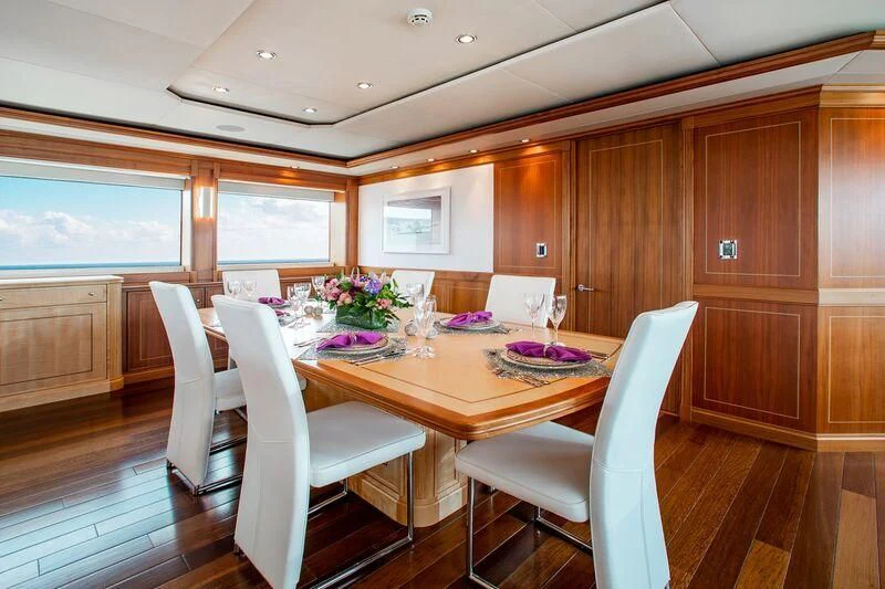 a dining table and chairs in a room with wood cabinets aboard BLACK SHEEP Yacht for Sale