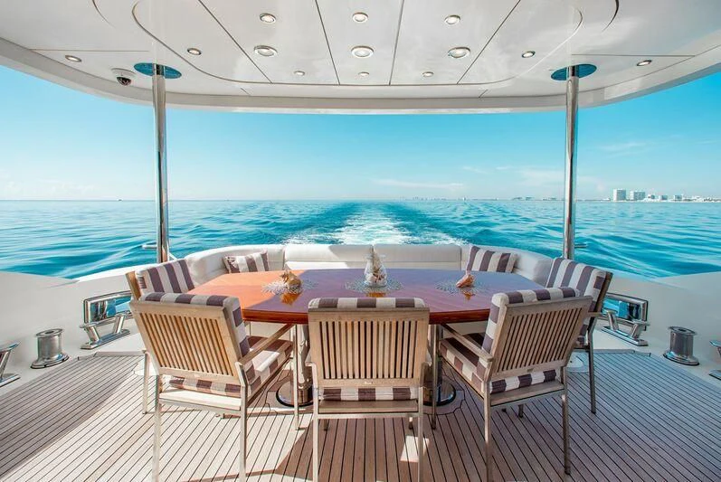 a table and chairs on a deck overlooking a beach aboard BLACK SHEEP Yacht for Sale