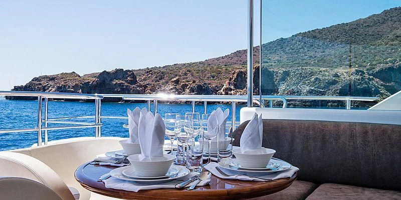 a table with plates and cups on it by a body of water aboard V6 Yacht for Sale