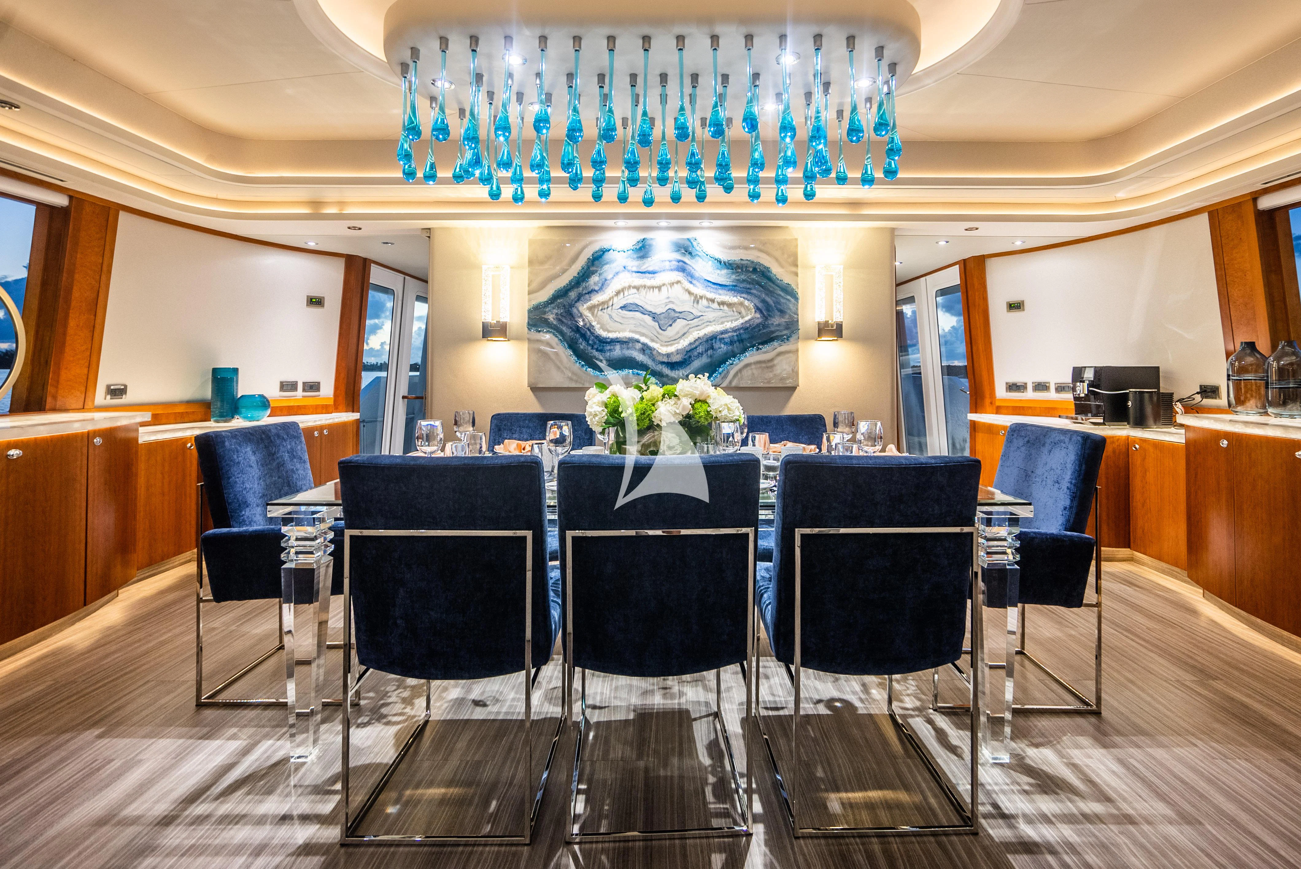 a room with blue chairs and a chandelier aboard KEMOSABE Yacht for Charter
