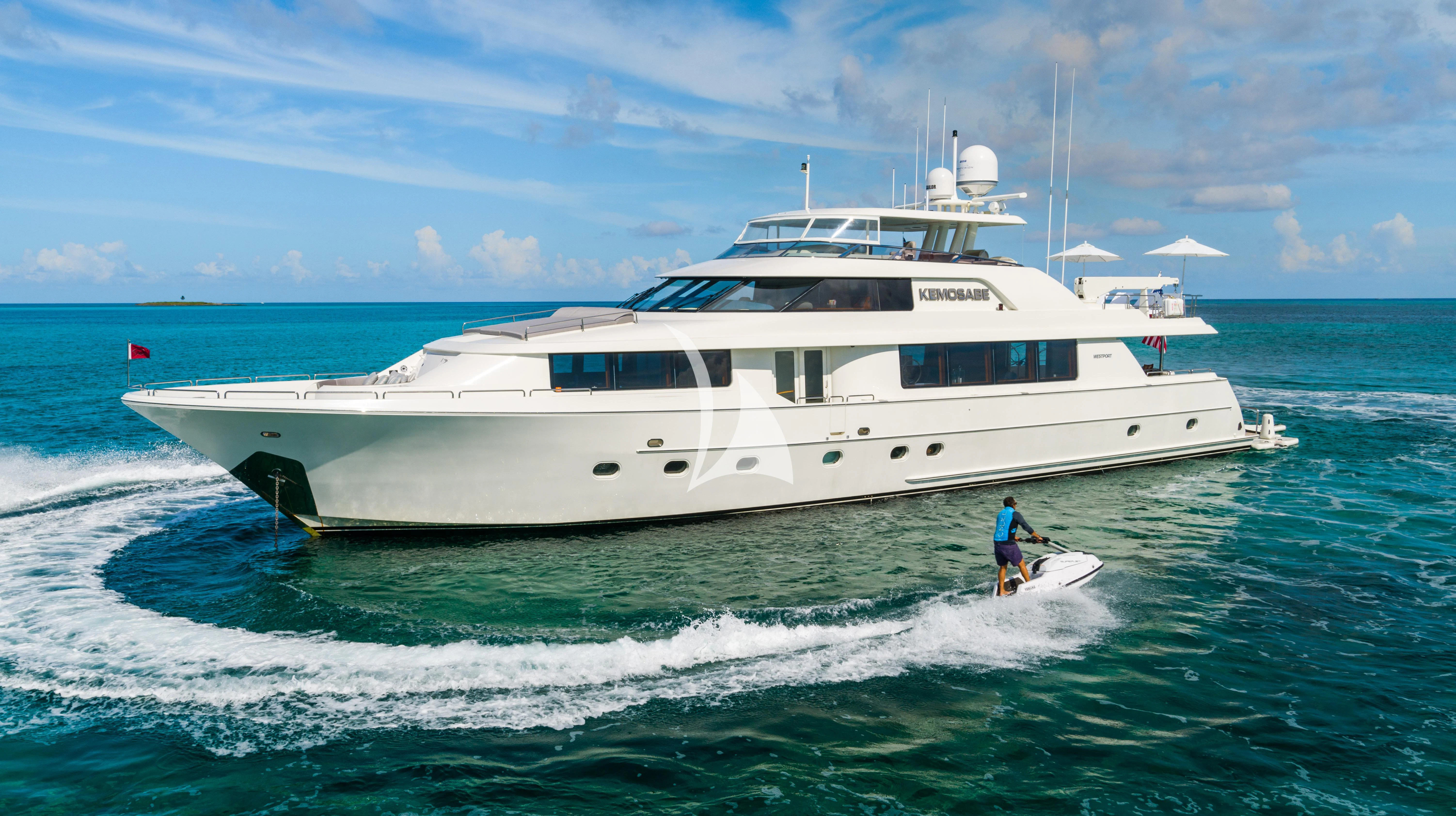 a person on a surfboard in front of a white boat aboard KEMOSABE Yacht for Charter