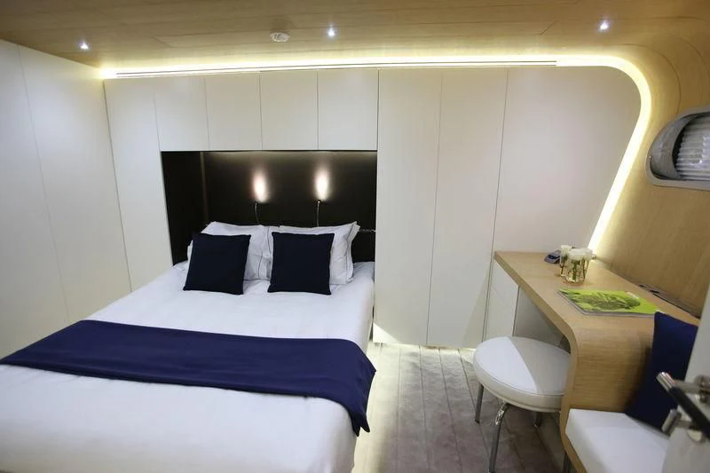 a room with a bed and desk aboard OCEAN SAPPHIRE Yacht for Sale