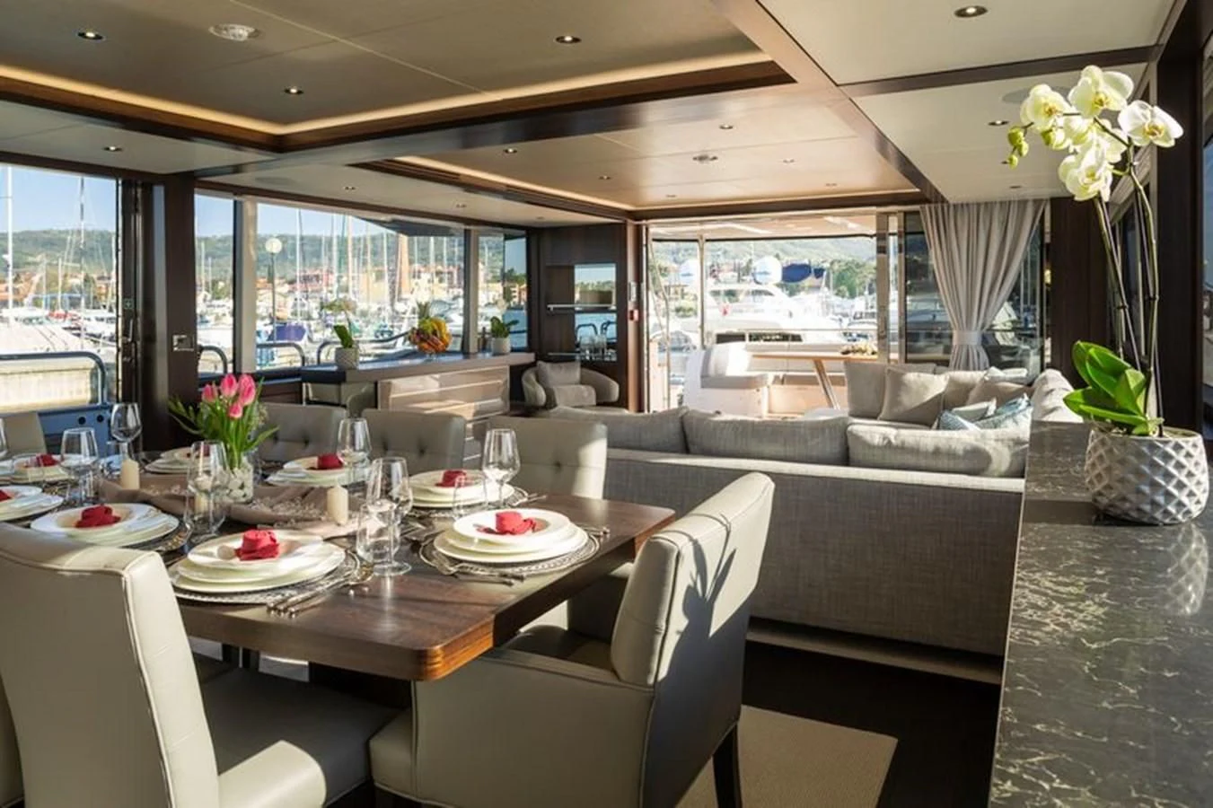 a dining table with chairs and a couch in a room with a large window aboard MR K IRISTON Yacht for Sale