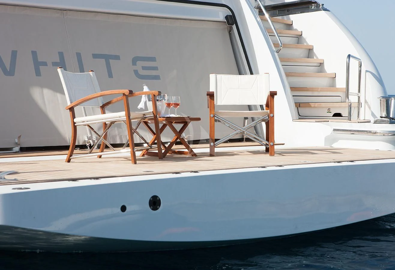 a white boat with chairs on the deck aboard DAISY D Yacht for Sale