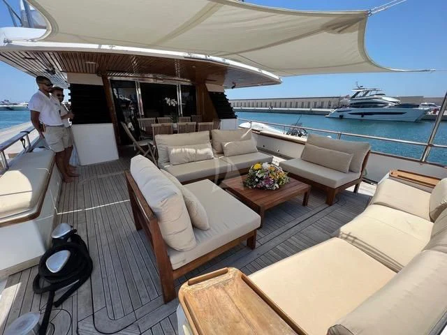a person standing on a deck of a boat with a large white sofa and a large blue and aboard ATLANTIC ENDEAVOUR Yacht for Charter