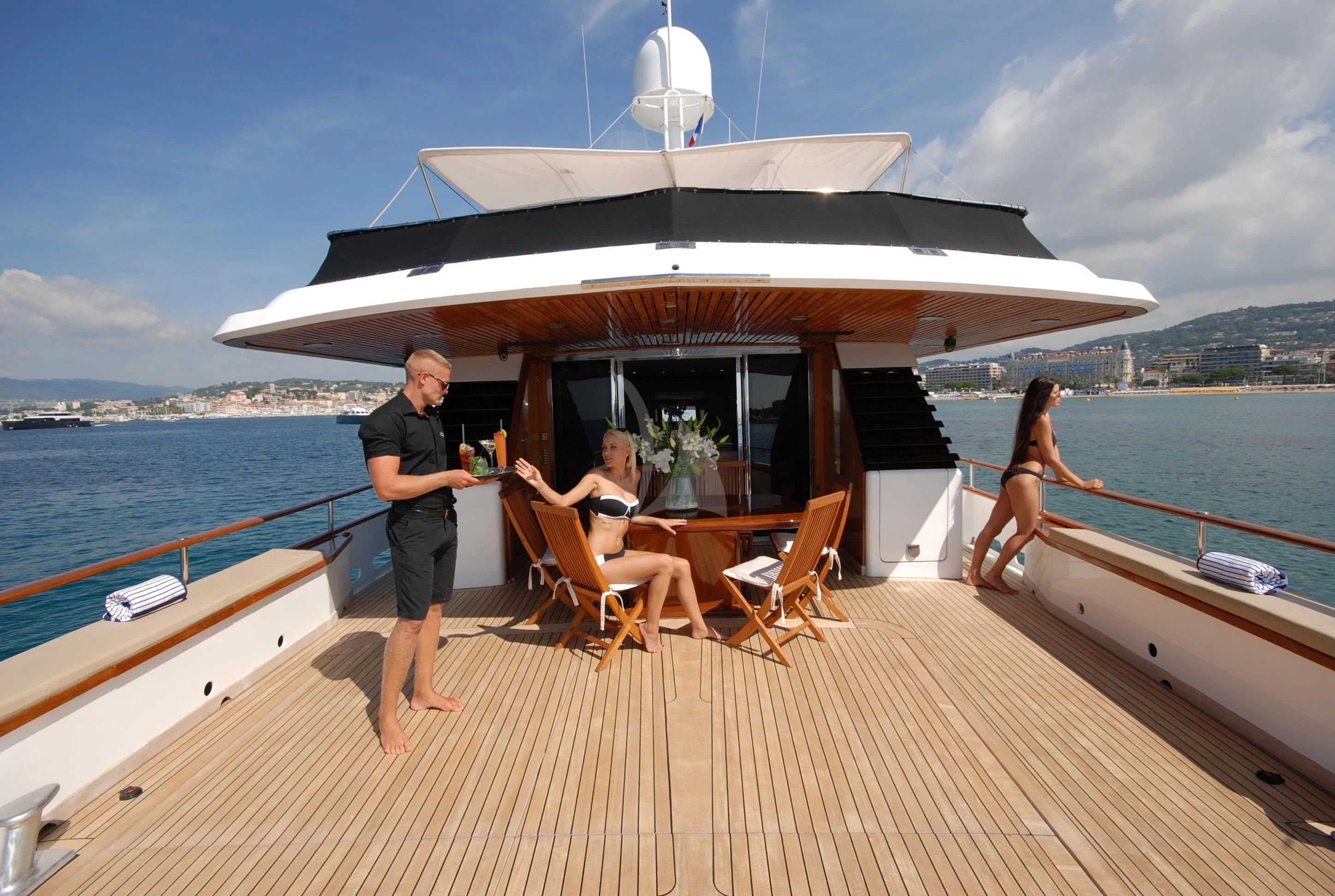 a man standing on a deck of a boat with a woman sitting on it aboard ATLANTIC ENDEAVOUR Yacht for Charter